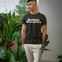 Man wearing a black t-shirt with 'Multiple Whoreosis' text in an indoor setting with plants.