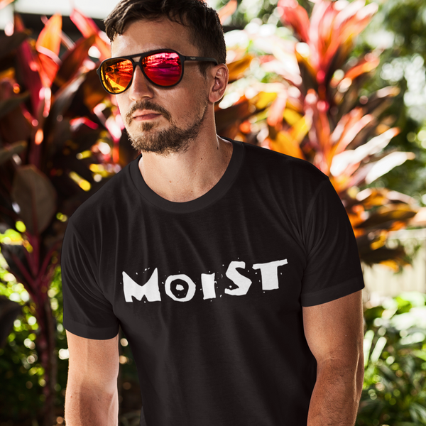 Man wearing a black t-shirt with 'MOIST' text, standing outdoors with plants in the background